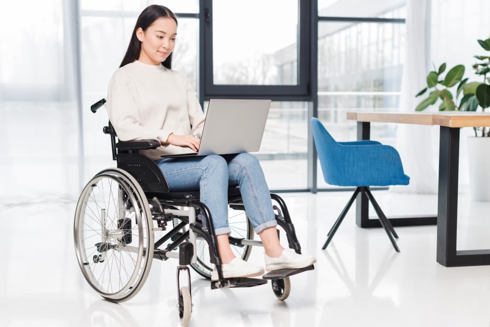 person with a spinal cord injury in wheelchair using laptop